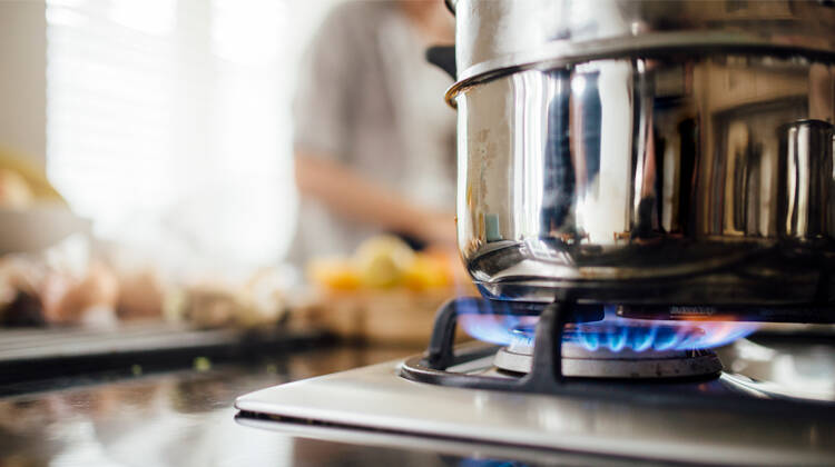 A stainless steel pot on top of the active burner of a natural gas stove