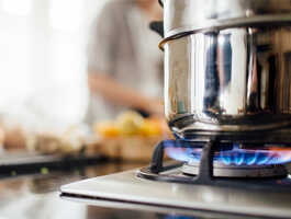 A stainless steel pot on top of the active burner of a natural gas stove